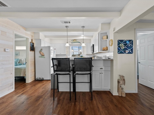 kitchen with visible vents, a peninsula, freestanding refrigerator, and white cabinetry