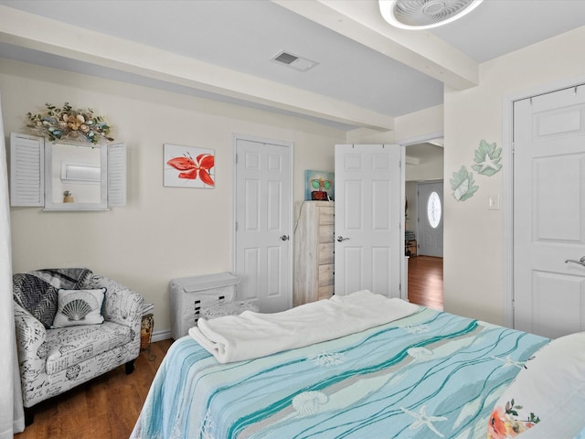 bedroom featuring dark wood-type flooring, beam ceiling, and visible vents