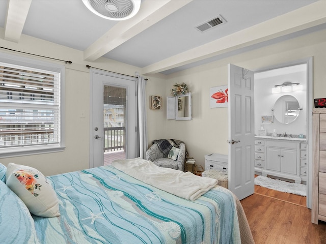 bedroom with beam ceiling, visible vents, ensuite bath, and wood finished floors