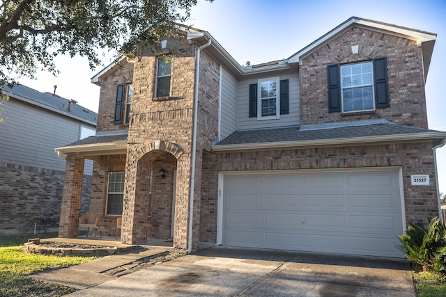 traditional home with driveway, roof with shingles, an attached garage, a porch, and brick siding