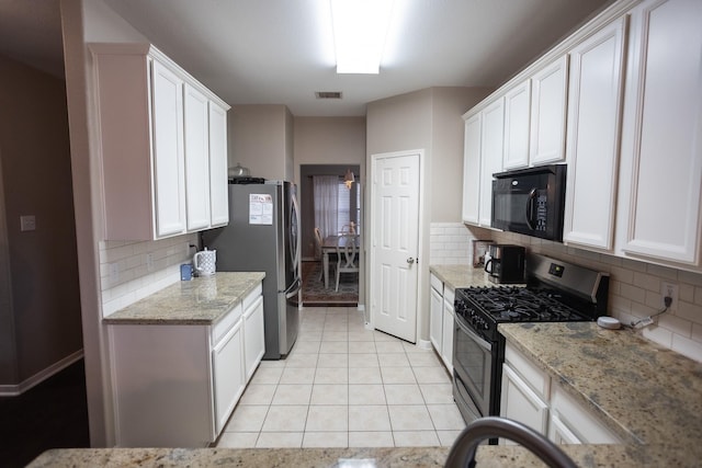 kitchen featuring appliances with stainless steel finishes, white cabinetry, visible vents, and light stone counters