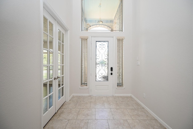 entrance foyer featuring light tile patterned floors, french doors, and baseboards