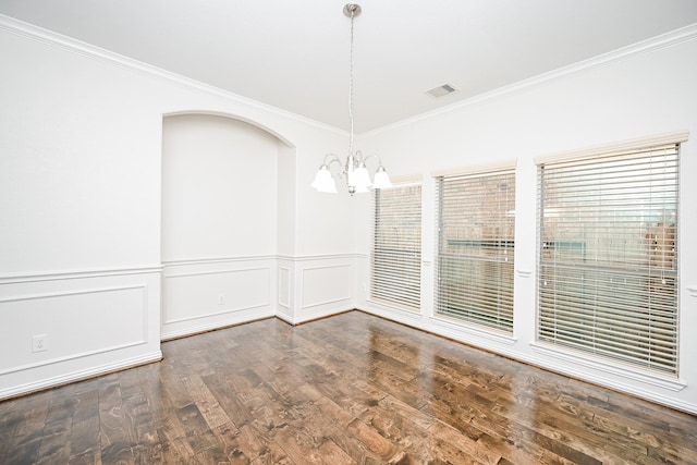 unfurnished room featuring a notable chandelier, wood finished floors, visible vents, wainscoting, and crown molding