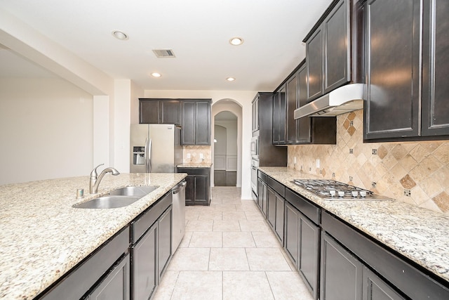 kitchen featuring visible vents, arched walkways, stainless steel appliances, under cabinet range hood, and a sink