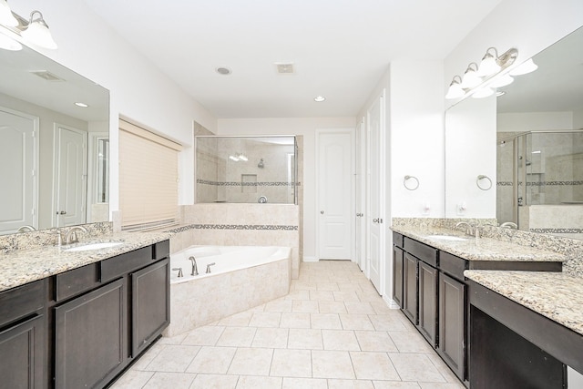 full bathroom with a stall shower, two vanities, a sink, and a bath