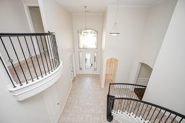 entryway with arched walkways, a high ceiling, baseboards, stairway, and crown molding