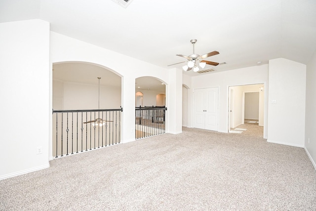 spare room featuring lofted ceiling, carpet flooring, visible vents, and a ceiling fan