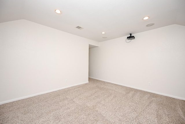 empty room with carpet floors, recessed lighting, visible vents, vaulted ceiling, and baseboards