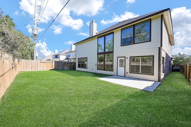 back of property featuring a yard, a fenced backyard, a chimney, and a patio