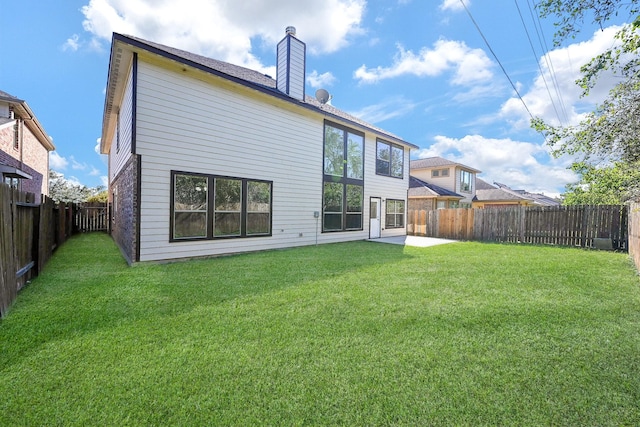 back of property with a patio, a chimney, a fenced backyard, and a lawn