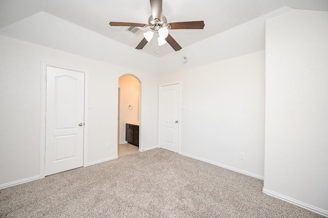 unfurnished bedroom with arched walkways, visible vents, light carpet, vaulted ceiling, and baseboards