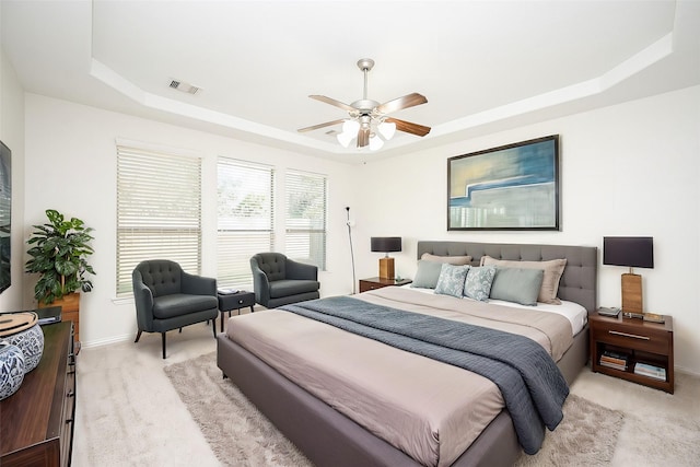 bedroom with baseboards, ceiling fan, a raised ceiling, and light colored carpet