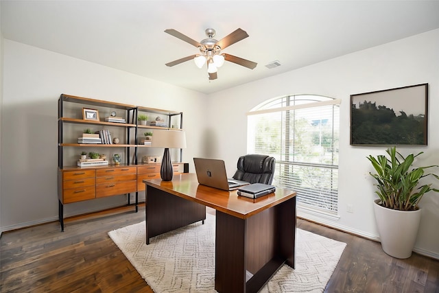 office featuring dark wood-style floors, visible vents, baseboards, and a ceiling fan