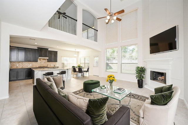 living room featuring light tile patterned floors, ceiling fan, a fireplace with raised hearth, and recessed lighting