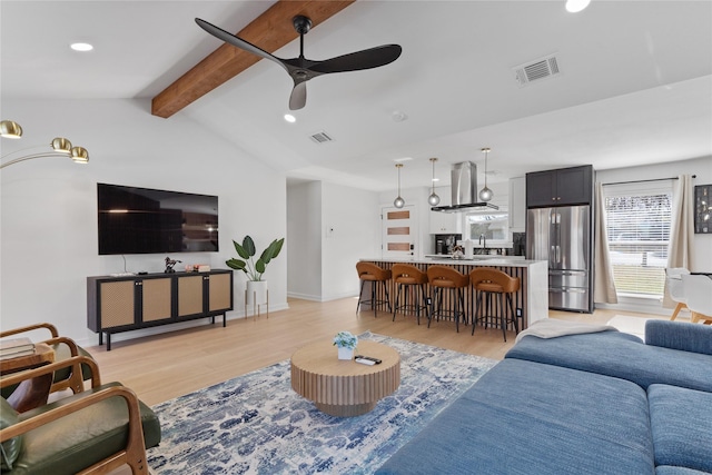 living room featuring visible vents, light wood-style flooring, lofted ceiling with beams, ceiling fan, and baseboards