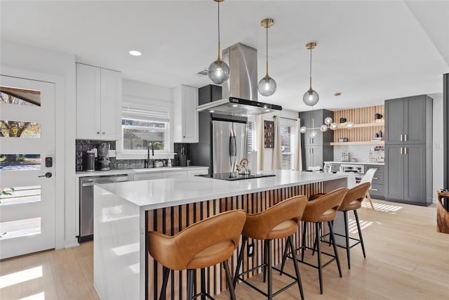 704 Emerald Wood Dr, Austin, TX 78745 - kitchen featuring stainless steel appliances, a sink, a center island with sink, light countertops, and island range hood