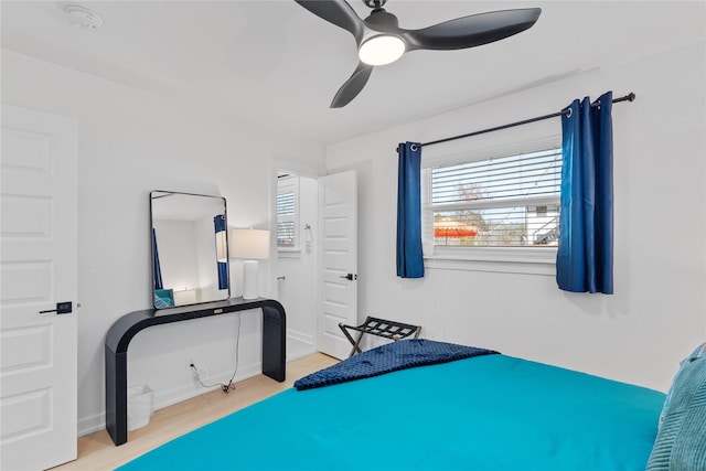 bedroom with ceiling fan, wood finished floors, and baseboards