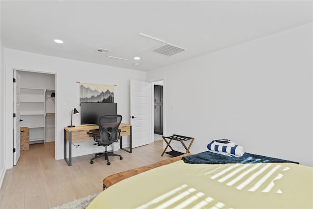 bedroom with visible vents, a walk in closet, and wood finished floors