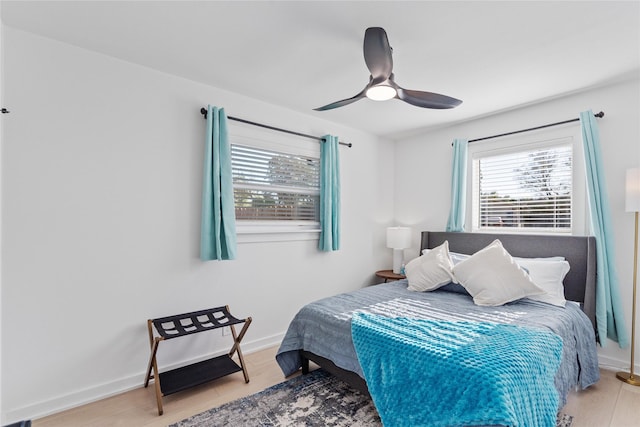 bedroom with ceiling fan, light wood-style flooring, and baseboards