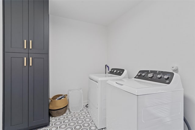 clothes washing area with cabinet space, light tile patterned floors, baseboards, and independent washer and dryer