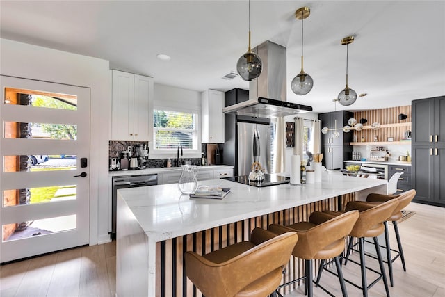 kitchen featuring gray cabinetry, stainless steel appliances, light stone countertops, open shelves, and decorative light fixtures