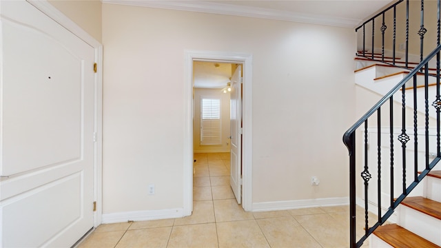 staircase featuring crown molding, baseboards, and tile patterned floors