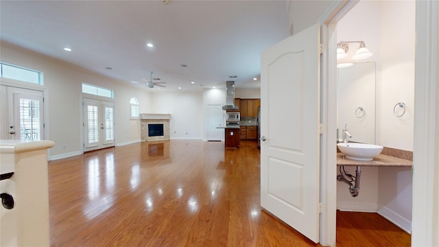 unfurnished living room with recessed lighting, a fireplace, a sink, and light wood-style floors