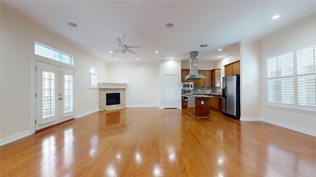 living room with light wood-style floors, a fireplace, baseboards, and ornamental molding