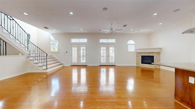 unfurnished living room with french doors, light wood finished floors, recessed lighting, baseboards, and stairs