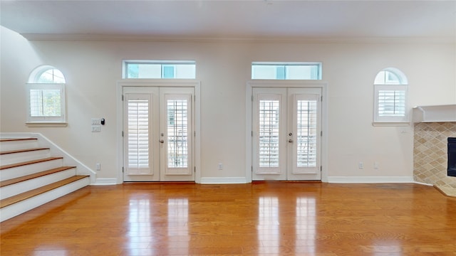 foyer entrance featuring ornamental molding, french doors, and light wood-style flooring