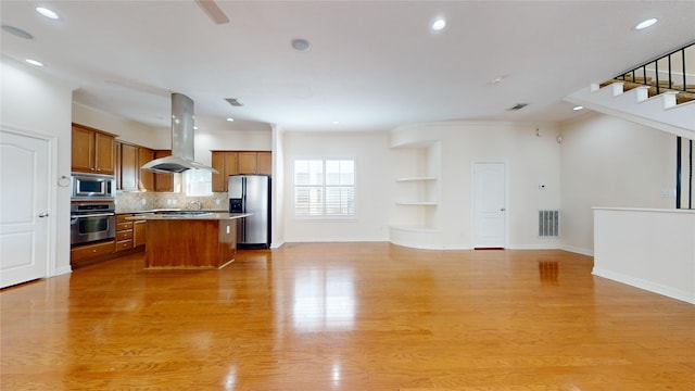 kitchen featuring a kitchen island, appliances with stainless steel finishes, island range hood, and open floor plan