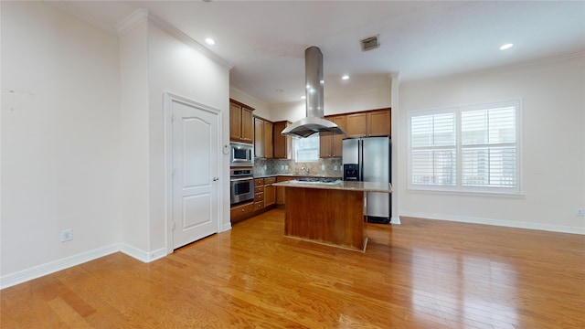 kitchen with a kitchen island, appliances with stainless steel finishes, brown cabinets, island exhaust hood, and light countertops