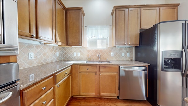 kitchen with appliances with stainless steel finishes, brown cabinetry, and a sink