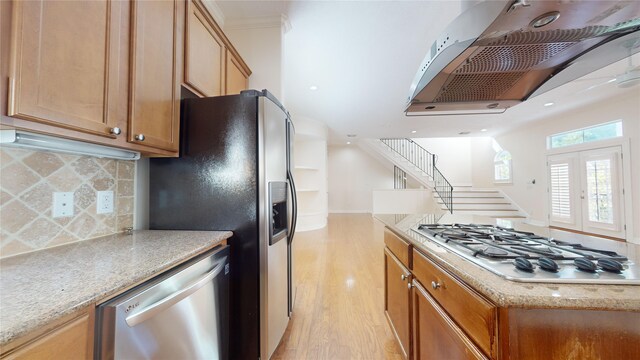 kitchen featuring decorative backsplash, light wood-style flooring, appliances with stainless steel finishes, range hood, and french doors