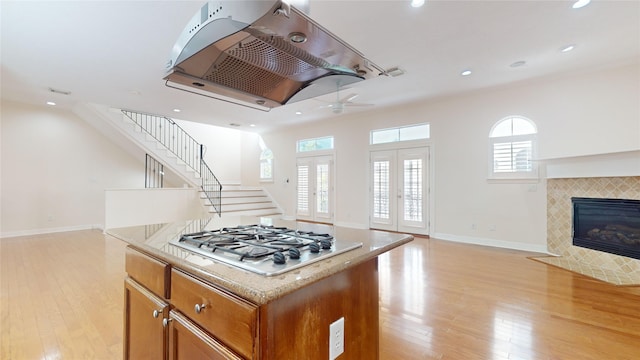 kitchen featuring open floor plan, light wood-style floors, a kitchen island, and stainless steel gas cooktop