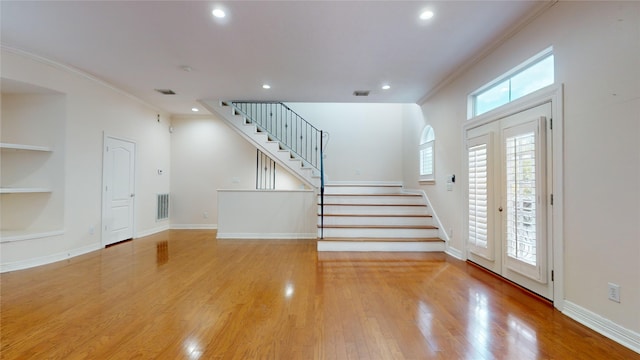 foyer with light wood-style flooring, stairs, visible vents, and ornamental molding