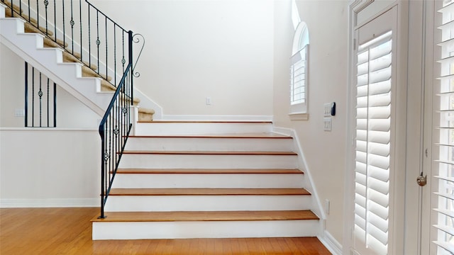 stairs with log walls, baseboards, and wood finished floors