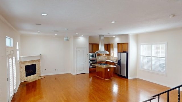 kitchen featuring brown cabinetry, a kitchen island, open floor plan, island exhaust hood, and stainless steel appliances