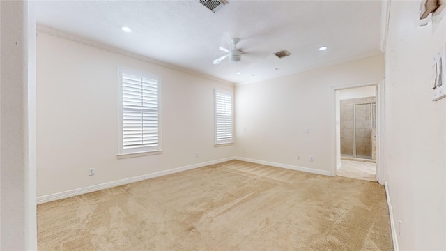 spare room with visible vents, ornamental molding, a ceiling fan, light carpet, and baseboards