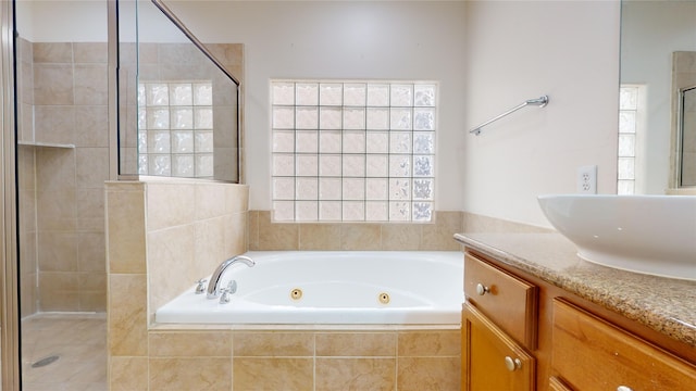 full bath featuring a stall shower, a jetted tub, and vanity