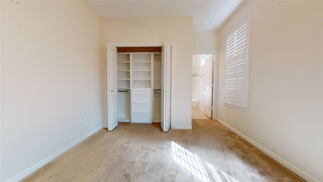 unfurnished bedroom featuring baseboards, a closet, and light colored carpet