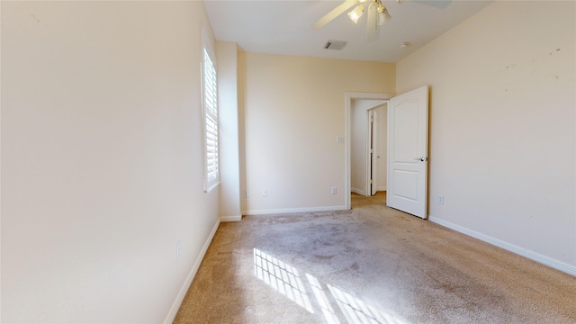 unfurnished room featuring a ceiling fan, light carpet, visible vents, and baseboards