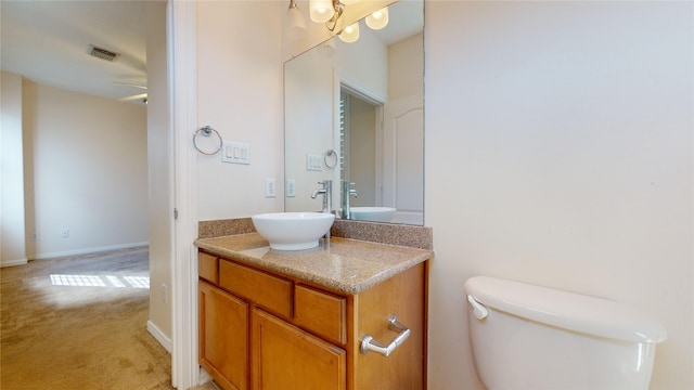 half bathroom featuring baseboards, visible vents, vanity, and toilet