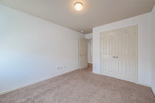 unfurnished bedroom featuring a textured ceiling, a closet, carpet flooring, and baseboards