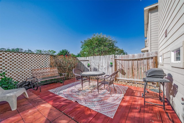 wooden terrace with area for grilling and a fenced backyard