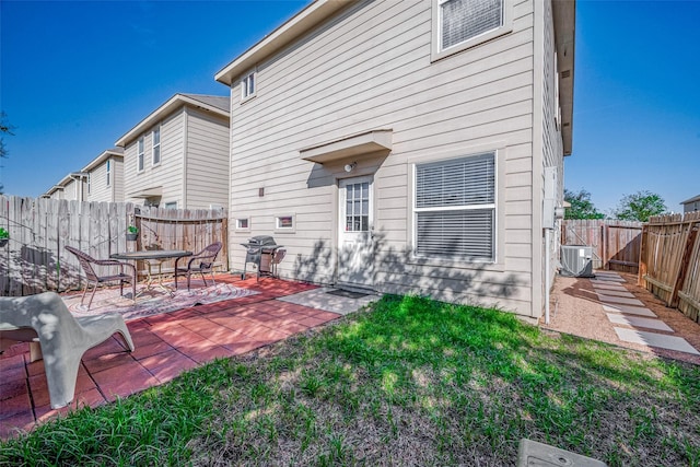 back of house featuring central air condition unit, a patio area, a fenced backyard, and a lawn