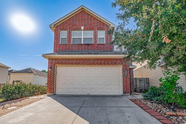 traditional-style home with brick siding, driveway, an attached garage, and fence