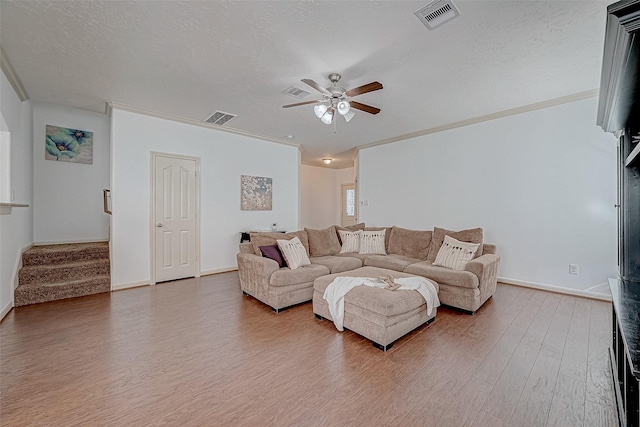 living area featuring a textured ceiling, stairs, wood finished floors, and visible vents