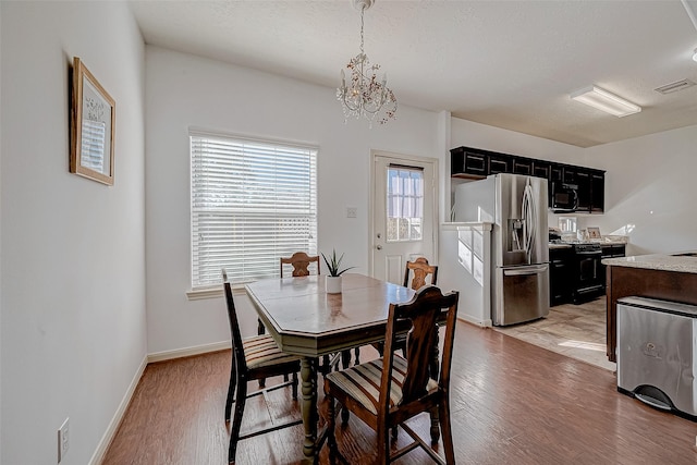 dining space featuring light wood-style floors, visible vents, baseboards, and an inviting chandelier