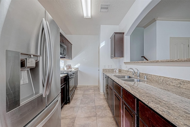 kitchen with a textured ceiling, a sink, visible vents, light stone countertops, and black appliances